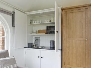 a kitchen with white cabinets and a door at The Little Cottage in Fittleworth