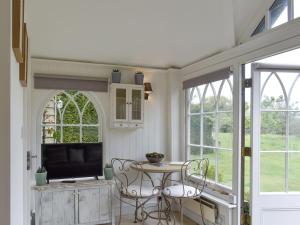 a living room with a table and a tv at The Little Cottage in Fittleworth