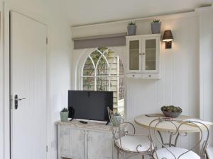 a living room with a table with chairs and a tv at The Little Cottage in Fittleworth