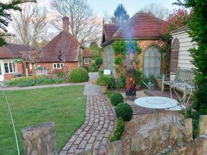 a house with a brick yard with a table in the backyard at The Little Cottage in Fittleworth