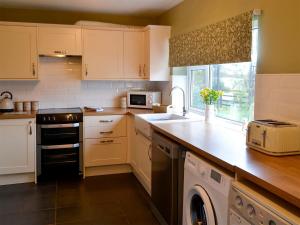 a kitchen with white cabinets and a sink and a dishwasher at Westfield Farm Cottage in Seaton Delaval
