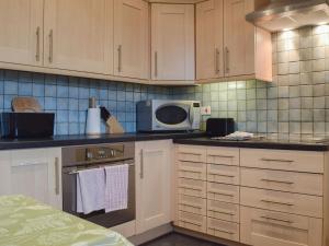 a kitchen with white cabinets and a microwave at Alice Cottage in Thurning