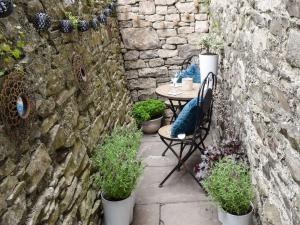 a patio with a table and chairs and plants at Christill Cottage in Burneside