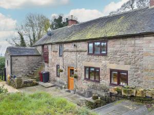 an old stone house with a orange door at Dewy Lane Farm House in Tansley