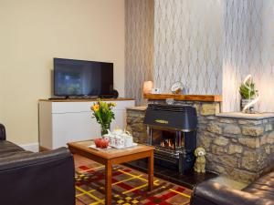 a living room with a stone fireplace and a tv at Morrice House in Ceres