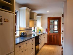 una cocina con armarios blancos y encimeras negras en Coulags Croft, en Ross-on-Wye