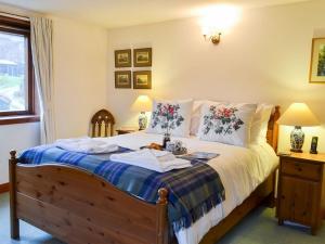 a bedroom with a bed and two lamps and a window at Coulags Croft in Ross on Wye