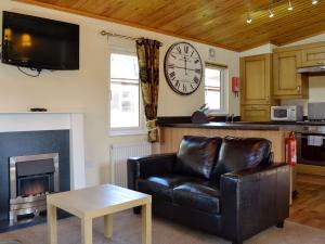 a living room with a couch and a clock on the wall at Lodge G- Uk33093 in Dinnet
