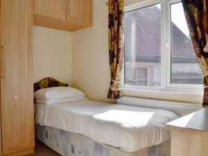 a small bedroom with a bed and a window at Lodge G- Uk33093 in Dinnet