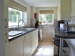 una cocina con armarios blancos y fregadero en Finkle Cottage en Pooley Bridge