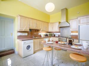 a kitchen with wooden cabinets and a counter with stools at Corby Castle - Courtyard - Uk34670 in Great Corby