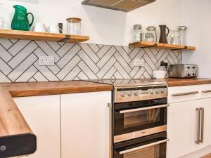 a kitchen with white cabinets and a stove at Gwynn House in Camborne