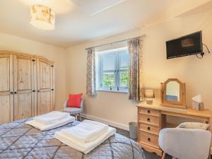 Lizzies Cottage في Skendleby: غرفة نوم مع سرير وتلفزيون على الحائط