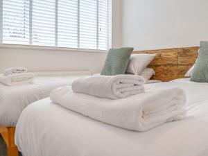 two beds with white towels on top of them at Gwynn House in Camborne