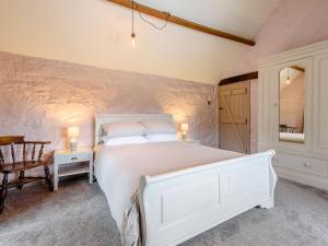Un dormitorio con una gran cama blanca y una mesa en Sitch Farm, en Matlock Bank