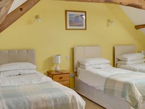 a bedroom with two beds and a table with a lamp at Leonard Barn in Stonehouse