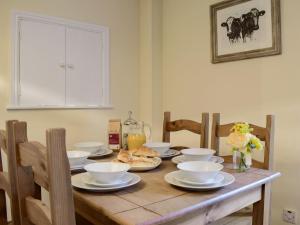 a wooden table with white bowls and plates on it at The Boyne Arms Cottage in Burwarton