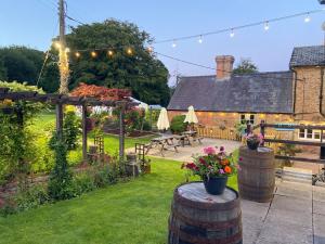 a garden with a patio and a house with lights at The Boyne Arms Cottage in Burwarton