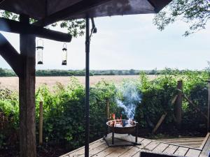 a fire pit on a deck with a view of a field at Toms Cabin - Uk35173 in Elmsted