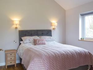 a bedroom with a bed with a love pillow on it at Cadno - Uk32825 in Cwrt-newydd