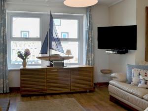 a living room with a tv and a boat on a dresser at Captains Cottage in Allonby