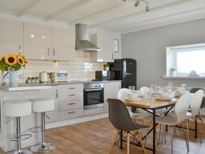 a kitchen with a table and chairs in a room at Captains Cottage in Allonby