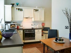 une cuisine avec des placards blancs et une table en bois dans l'établissement Porters Lodge, à Axminster