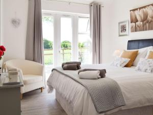a white bedroom with a large bed and a chair at The Duck House in Ruckinge