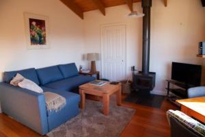 sala de estar con sofá azul y estufa de leña en Rose Cottage. Cosy, eco-friendly cottage in Yarra Glen., en Yarra Glen