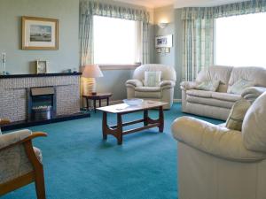 a living room with couches and a table and a fireplace at Bel-mar in Whithorn