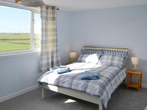 1 dormitorio con 1 cama con ventana y toallas. en Bel-mar en Whithorn