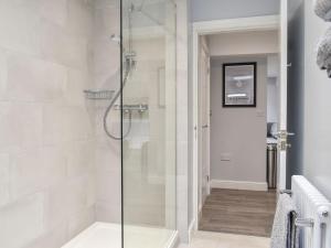 a shower with a glass door in a bathroom at Woodgate Cottage in Dalton in Furness