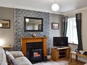 a living room with a fireplace and a tv at Cuillin View House - Uk12528 in Arisaig