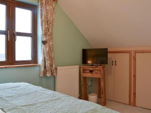 a bedroom with a bed and a flat screen tv at The Old Forge in Burshill