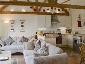 a living room with two couches and a kitchen at Sunflower Holiday Cottage in Alford