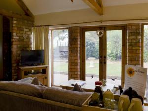 a living room with a couch and a tv at Sunflower Holiday Cottage in Alford