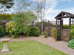 un jardín con una valla de madera y una pérgola de madera en Sunflower Holiday Cottage, en Alford