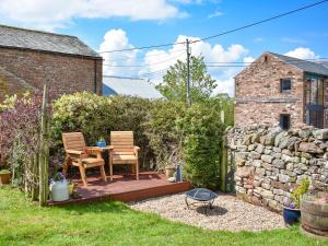a patio with two chairs and a table in a garden at Helm View in Blencarn
