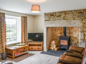 a living room with a stone fireplace and a couch at Lower Colvannick in Cardinham