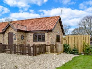 a brick house with a wooden fence in front of it at Oxley Cottage in Orby
