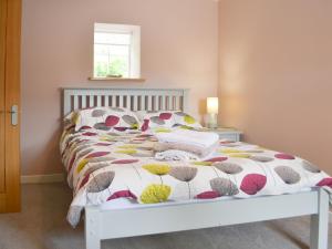 a bedroom with a bed with a floral bedspread at Mansefield Cottage in Boyndie