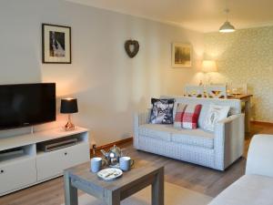 a living room with a couch and a tv at Four Winds in Drumnadrochit