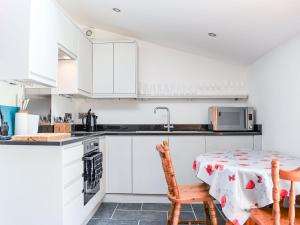 cocina con armarios blancos, mesa y sillas en Slade Cottage - Uk35027, en Highbray