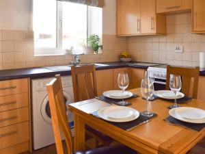 a kitchen with a wooden table with plates and wine glasses at Abbotts Close Cottage in Bagby