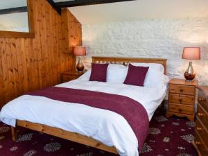1 dormitorio con 1 cama grande con sábanas blancas y almohadas moradas en Heron Cottage-uk32944, en Great Salkeld