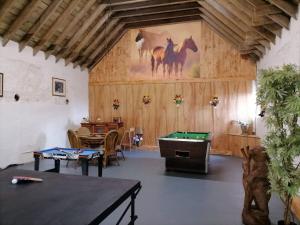 a room with a pool table and a painting of horses at Old Stable Cottage in Uplawmoor