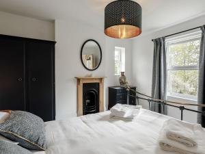 a bedroom with a bed and a mirror at Spinney Cottage in Woodford