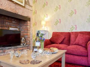 uma sala de estar com um sofá vermelho e uma mesa em St Cuthberts Retreat em Wooler