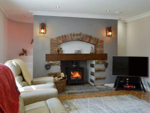 a living room with a fireplace and a tv at Brynllefrith Farmhouse in Cymmer
