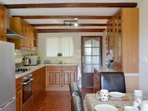 a large kitchen with wooden cabinets and a table at Brynllefrith Farmhouse in Cymmer